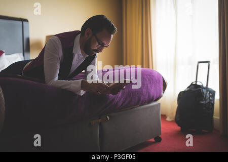 Businessman using digital tablet on bed Stock Photo