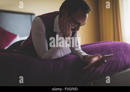 Businessman using digital tablet in bedroom Stock Photo