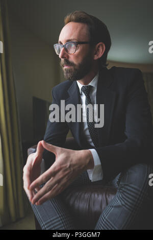 Thoughtful businessman sitting on arm chair Stock Photo