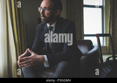 Thoughtful businessman sitting on arm chair Stock Photo