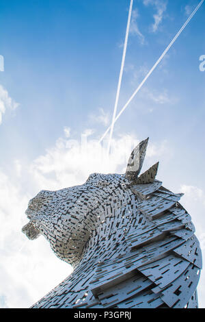 Head of one of the Kelpies sculptures in Helix Park, Falkirk. View from behind with plane fumes in the sky ressembling the Scottish Saltire flag Stock Photo