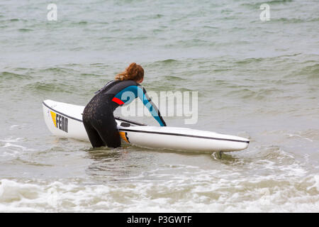 Young woman about to get in a surf ski surfski at Branksome Chine, Poole, Dorset, England UK in June Stock Photo