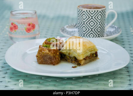 21.05.2018, Selcuk, Turkey: Baklava pieces, water and turkish coffee are on a table. The traditional pastry is a pastry made of leafy or filo pastry stuffed with sugar syrup filled with chopped walnuts, almonds or pistachios. Photo: Jens Kalaene/dpa central image/dpa | usage worldwide Stock Photo