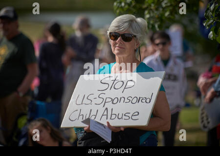 Sheridan, Oregon, USA. 18 June, 2018. A woman holds a sign against the Trump administration policy of separating children from their parents at the US-Mexico border during a vigil outside a federal detention center in Sheridan, Oregon, USA. Credit: Paul Jeffrey/Alamy Live News