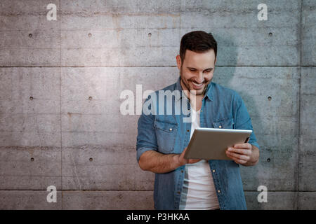 Young handsome successful entrepreneur looking on his tablet, checking plans before starting to work on construction site. Stock Photo