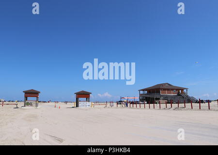 American beach lifestyle. Beach with blue sky on the Gulf Coast, Texas, Galveston Island, USA. Beach entrance for cars, campers to drive on the beach. Stock Photo