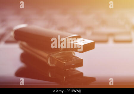 USB flash cards lying on black laptop case in front of his keyboard. Virtual memory storage with USB output Stock Photo