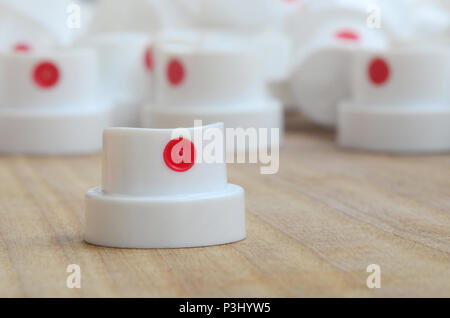 Several new plastic nozzles from a paint sprayer that lie on a wooden surface against a gray wall background. The concept of street art and graffiti Stock Photo