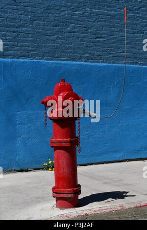 Bright red fire hydrant against blue wall  in Silverton Stock Photo