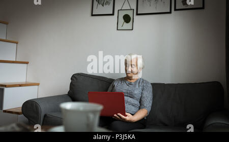 Senior woman using laptop in living room Stock Photo