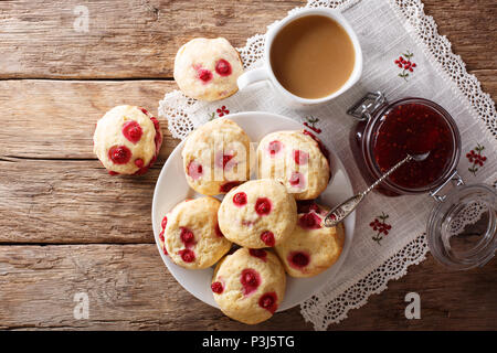 English buns sconces with red currants are served with English tea and jam close-up on the table. horizontal top view from above Stock Photo