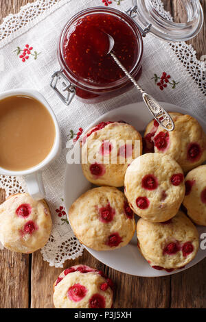 English sconces biscuits with red currants are served with tea and milk close-up on the table. Vertical top view from above Stock Photo