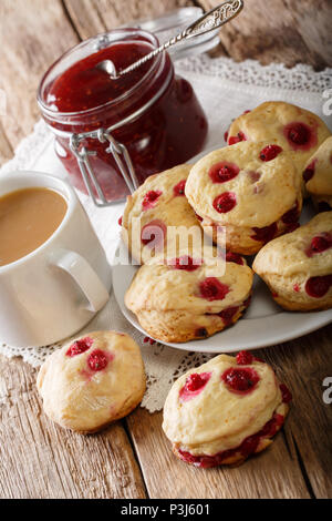 Delicious sconces biscuits with red currants are served with tea with milk and jam close-up on the table. vertical Stock Photo