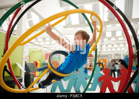 Schoolboy in science centre using human gyroscope, side view Stock Photo