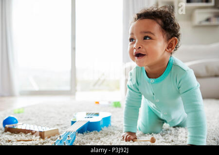 Happy mixed race toddler boy crawling in sitting room Stock Photo