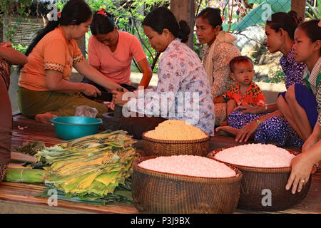 The day before a Khmer wedding the family prepares the wedding meal wrapping rice and sweetmeats in banana leaves ready for cooking. Stock Photo