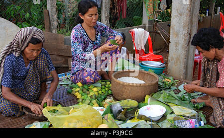 The day before a Cambodian wedding the family prepares the wedding feast. Wrapping sweetmeats in parcels of banana leaves. Stock Photo