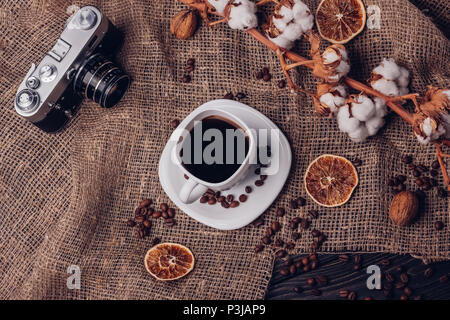 Coffee with retro camera dry cotton and oranges with walnuts on the table Stock Photo