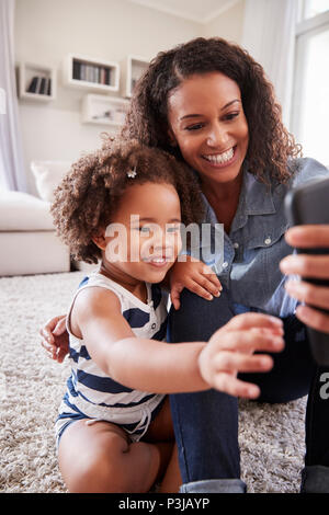 Mother and toddler daughter looking at photos on smartphone Stock Photo