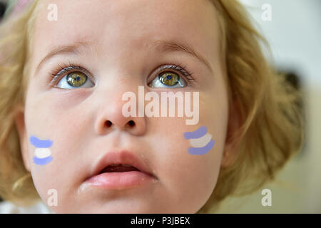 Portrait of a baby girl looking up with her beatuful eyes and with argentinian flags painted on her cheeks on a patriot day Stock Photo