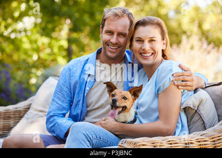 Happy young couple  sitting with their pet dog in the garden Stock Photo