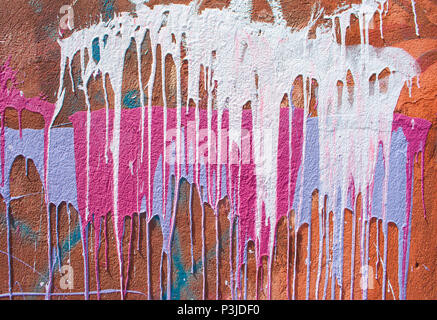 Colorful paint drips on a red wall. Stock Photo