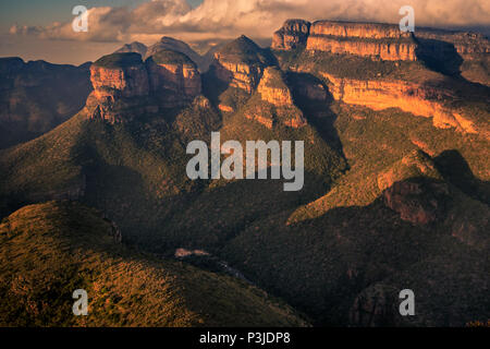 Wide view of the Three Rondavels and surrounding mountain cliffs in golden light just before sunset. Mpumalanga, South Africa Stock Photo