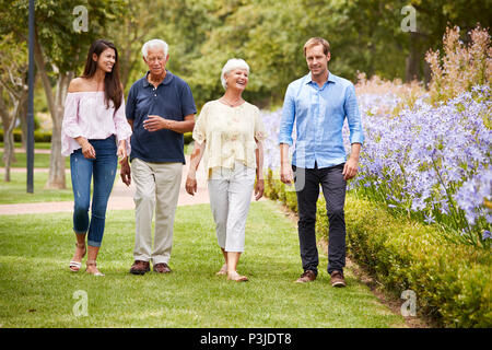 Senior Parents With Adult Children On Walk In Park Stock Photo