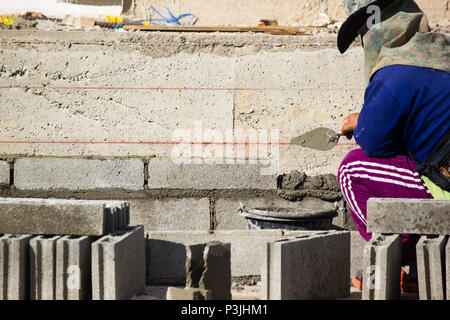 Mason or Brick builders are building cement brick wall in construction site.  Workers are building buildings or buildings for housing. Stock Photo