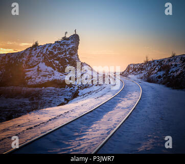 Man stands on top of the rock posing railroad railway train tracks Anchorage Alaska Stock Photo