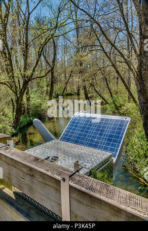 Vertical shot of a Solar Energy Panel powering a Smoky Mountain research station set up next to a stream going through the trees. Stock Photo