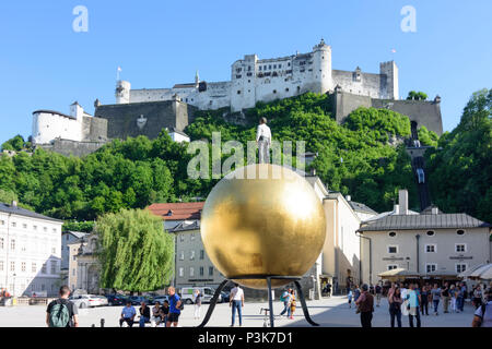 Salzburg: square Kapitelplatz, Hohensalzburg Castle, Sphaera, a sculpture of a man on a golden sphere in Austria, Salzburg, Stock Photo