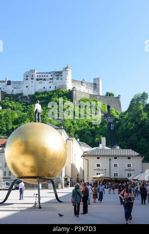 Salzburg: square Kapitelplatz, Hohensalzburg Castle, Sphaera, a sculpture of a man on a golden sphere in Austria, Salzburg, Stock Photo