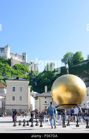 Salzburg: square Kapitelplatz, Hohensalzburg Castle, Sphaera, a sculpture of a man on a golden sphere in Austria, Salzburg, Stock Photo