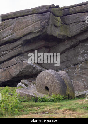 Giant millstones resting in a field near a rock formation in the peak district near stanage edge in great britain Stock Photo