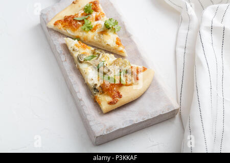 Two pieces of cheese pizza on white cutting board Stock Photo