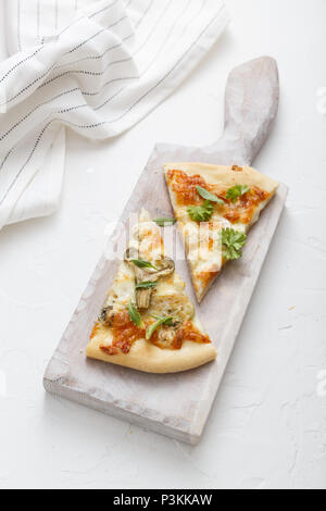 Two pieces of cheese pizza on white cutting board Stock Photo