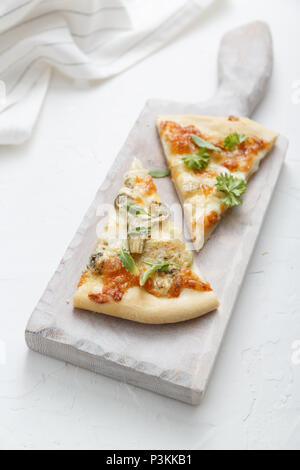 Two pieces of cheese pizza on white cutting board Stock Photo