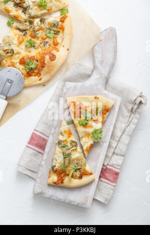 Two pieces of pizza with artichoke on white cutting board Stock Photo