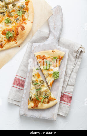 Two pieces of pizza with artichoke on white cutting board Stock Photo