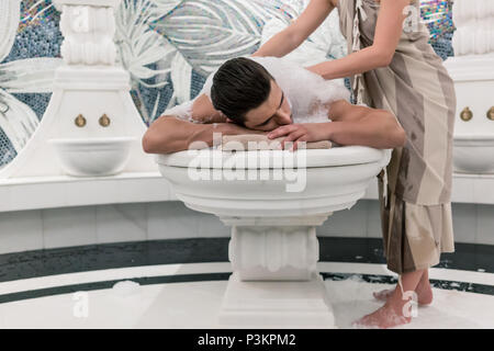 Relaxed man lying down on hot marble bed during traditional Turkish bath Stock Photo