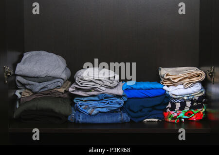 Neat stacks of different clothes lie on a shelf in the closet Stock Photo