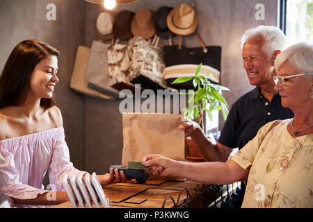 Senior Customers Buying Goods In Store Using Contactless Payment Stock Photo