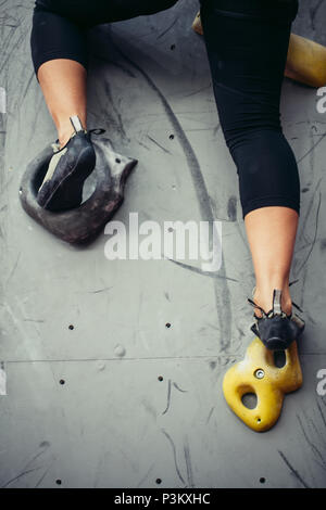 Bottom close up view of rock climber female feet on artificial climbing wall. Stock Photo