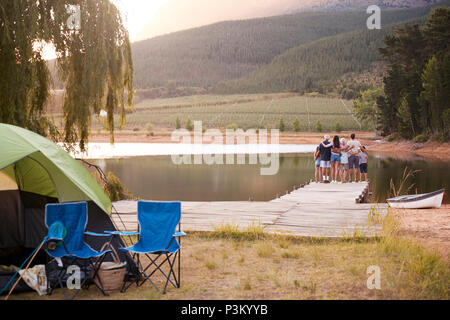 Tourist tent, backpack, fishing rods on countryside with lake