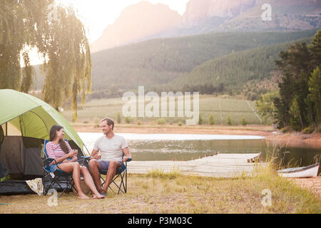 Couple Enjoying Camping Vacation By Lake Making A Toast Stock Photo