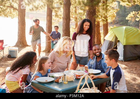 Family With Friends Camp By Lake On Hiking Adventure In Forest Stock Photo