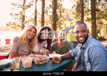 Portrait Of Couple With Friends Camping By Lake In Forest Stock Photo