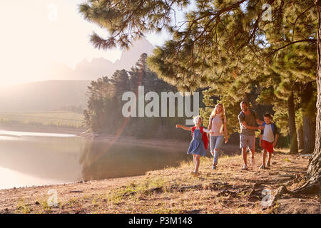 Children Walk By Lake With Parents On Family Hiking Adventure Stock Photo