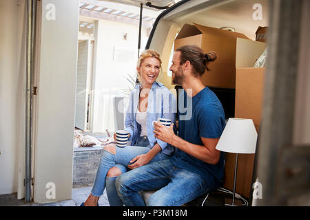 Couple Taking A Break In Back Of Removal Truck On Moving Day Stock Photo